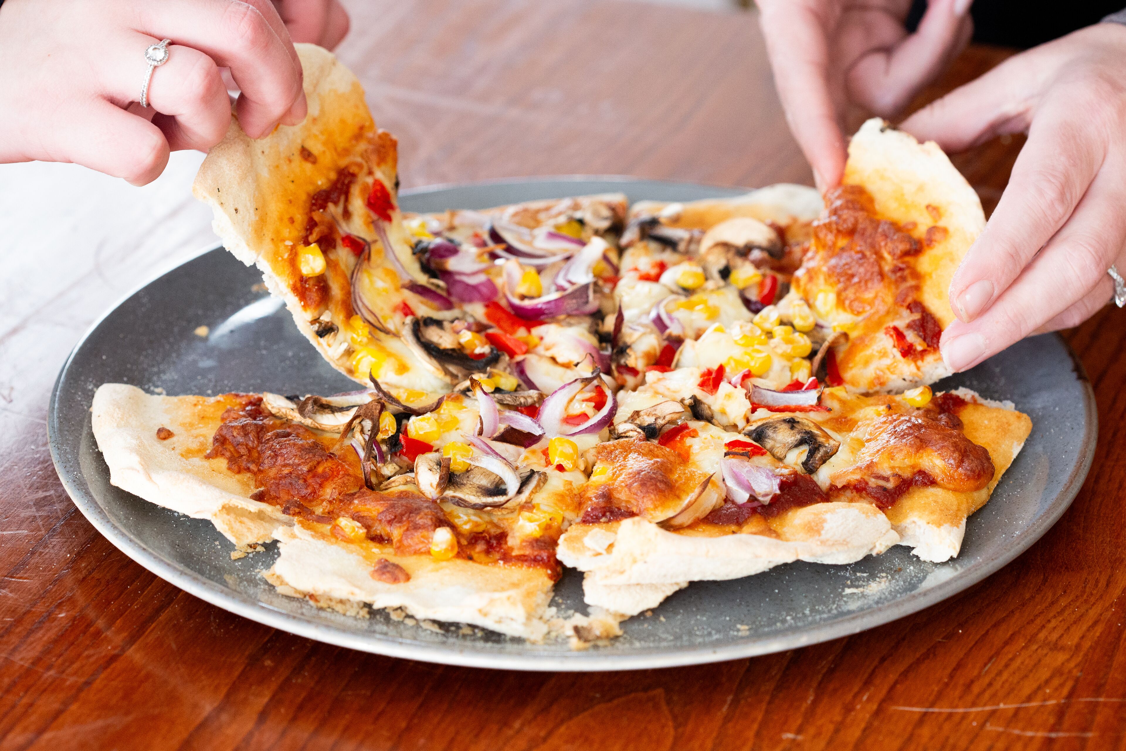 Une pizza garnie de divers ingrédients, servie sur une assiette en métal.