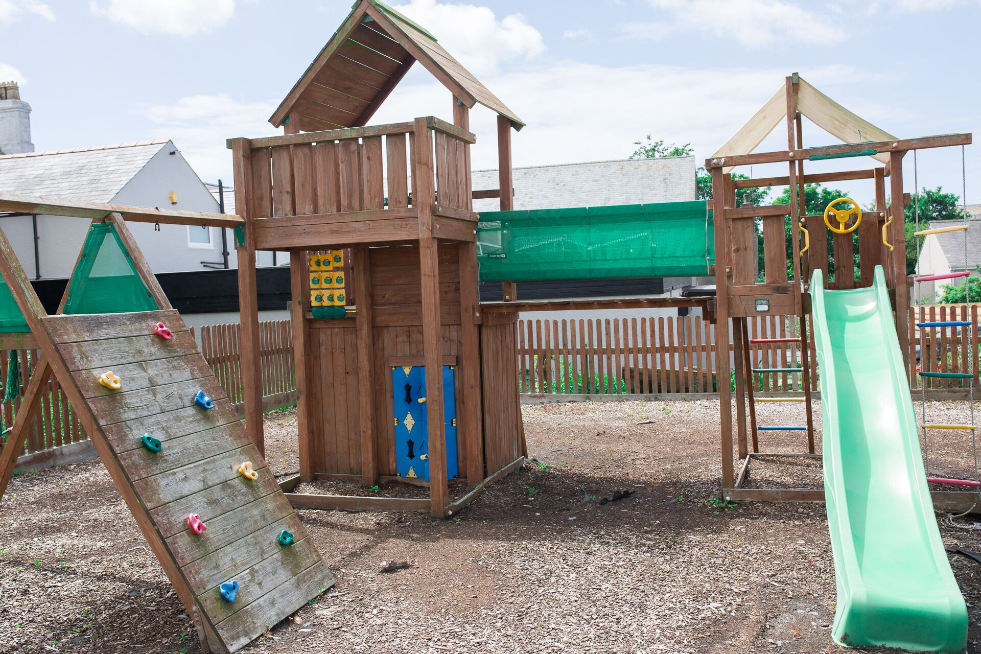 A wooden play structure with a slide and climbing wall.