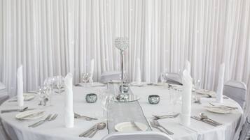 A round table set for a formal event with white tablecloths, silverware, and crystal glassware.