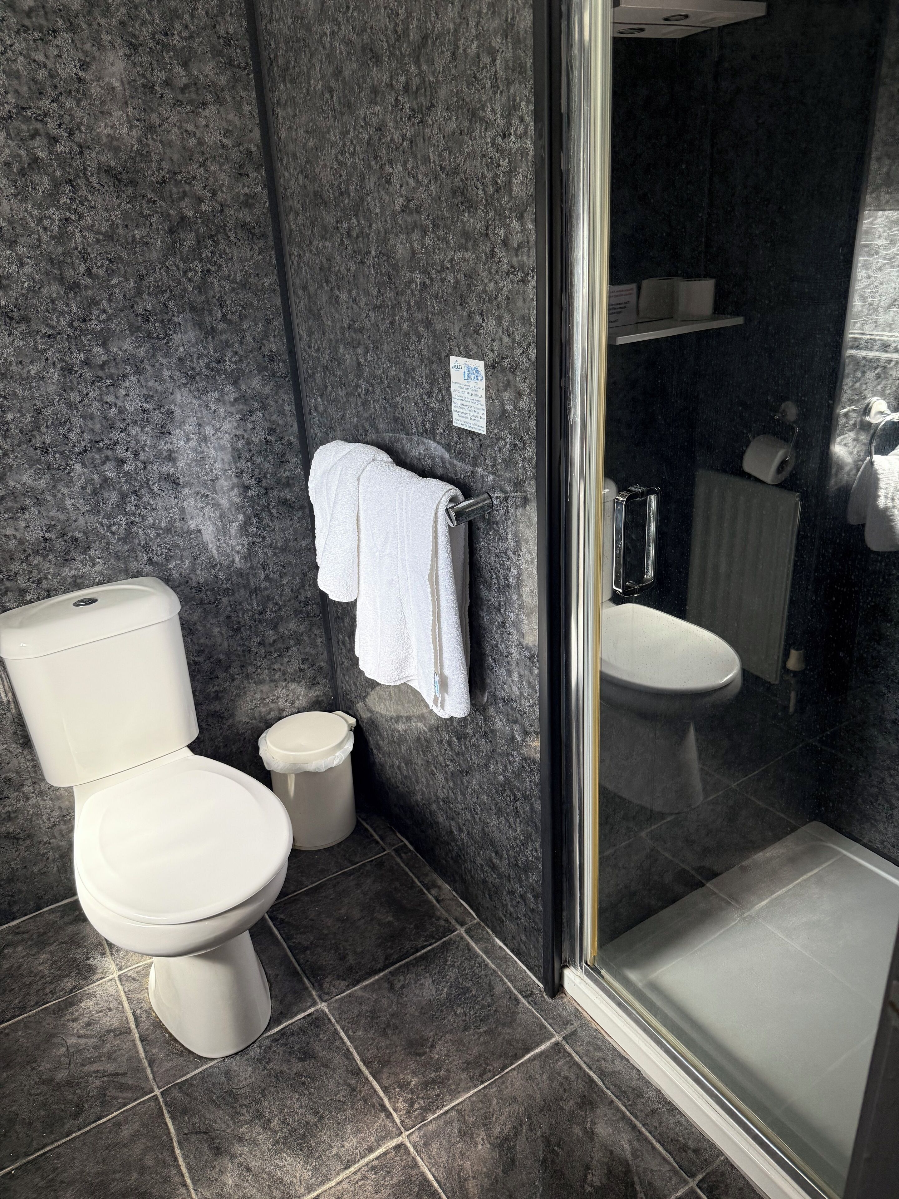Et badeværelse med toilet, håndvask og bruseområde.