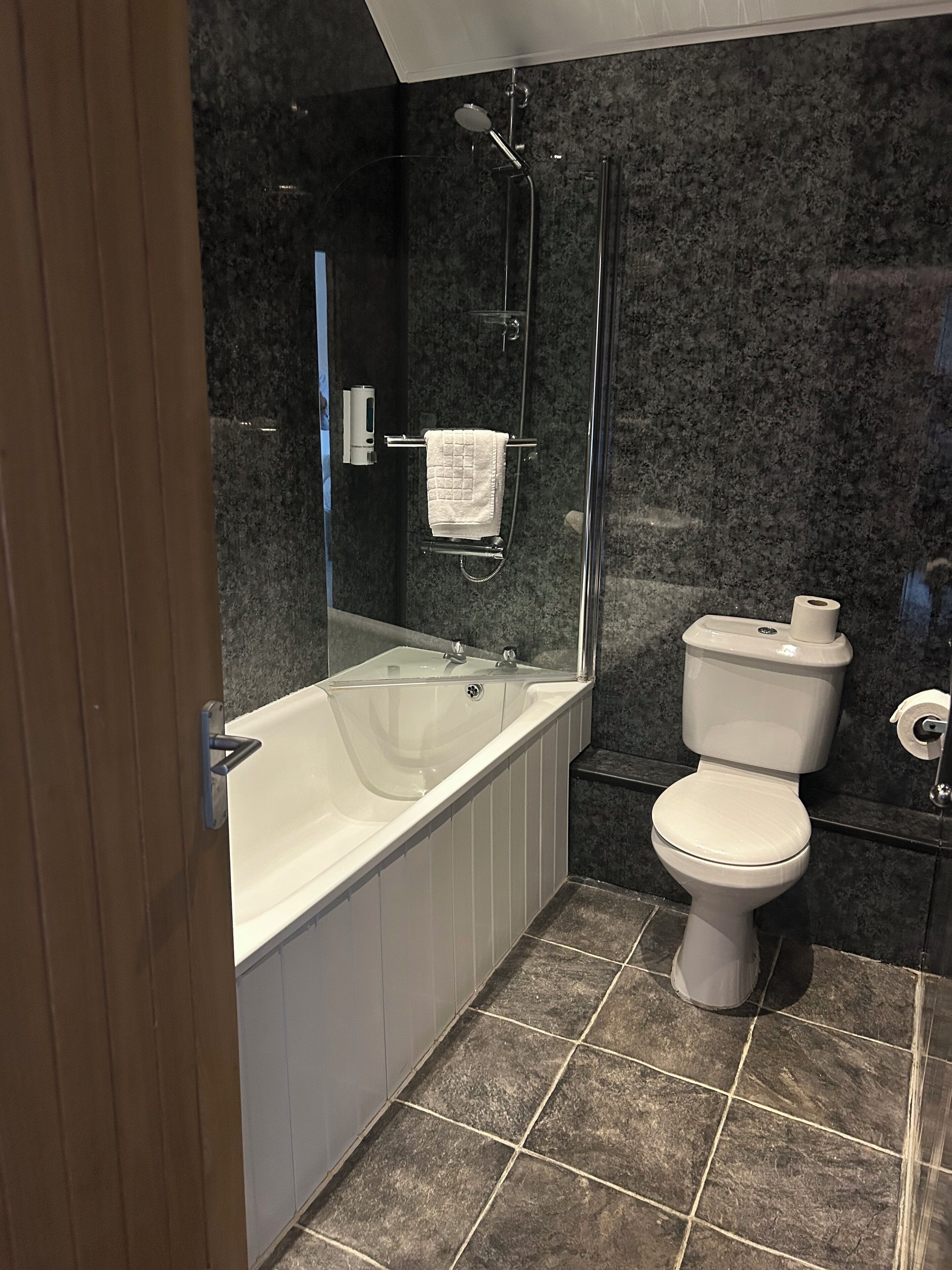 A modern bathroom with a bathtub, toilet, and shower.