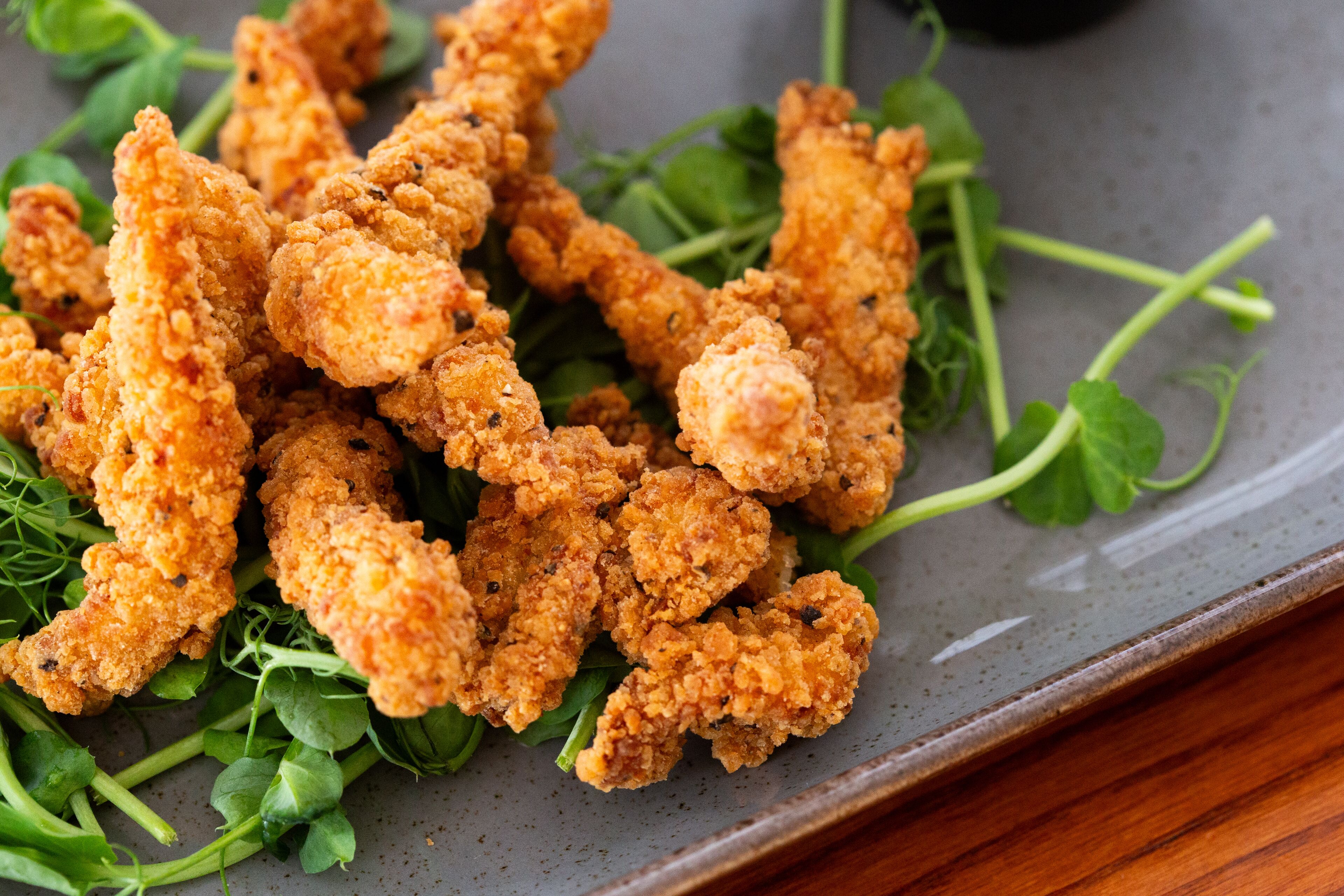 Un plato de pollo frito con vegetales de hoja verde.