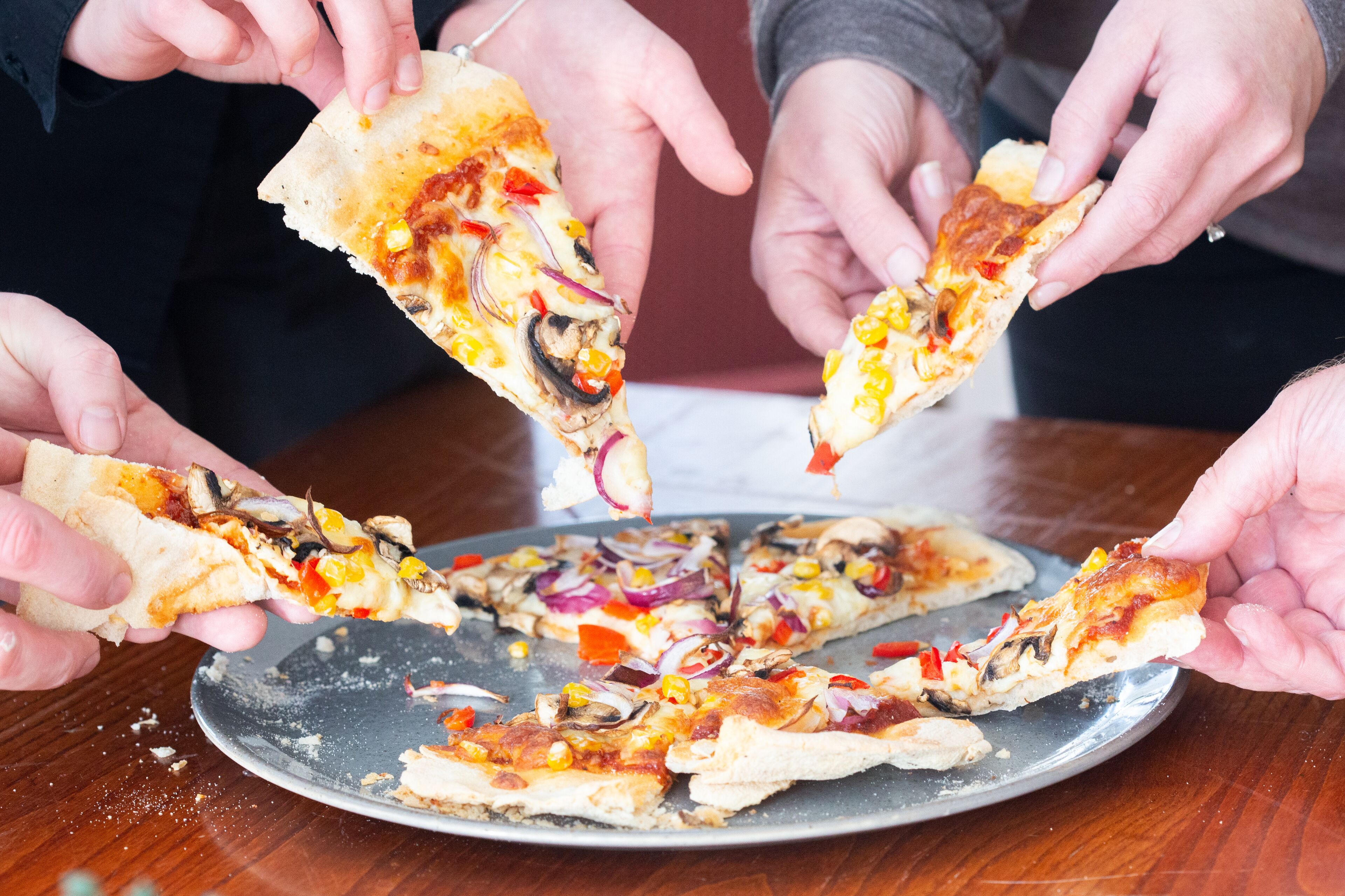 Um grupo de pessoas segurando fatias de pizza.