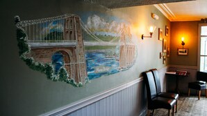 Une fresque représentant le pont de Menai est peinte sur un mur. L’espace d’accueil comprend un banc en bois, une petite table et des lampes fixées au mur.