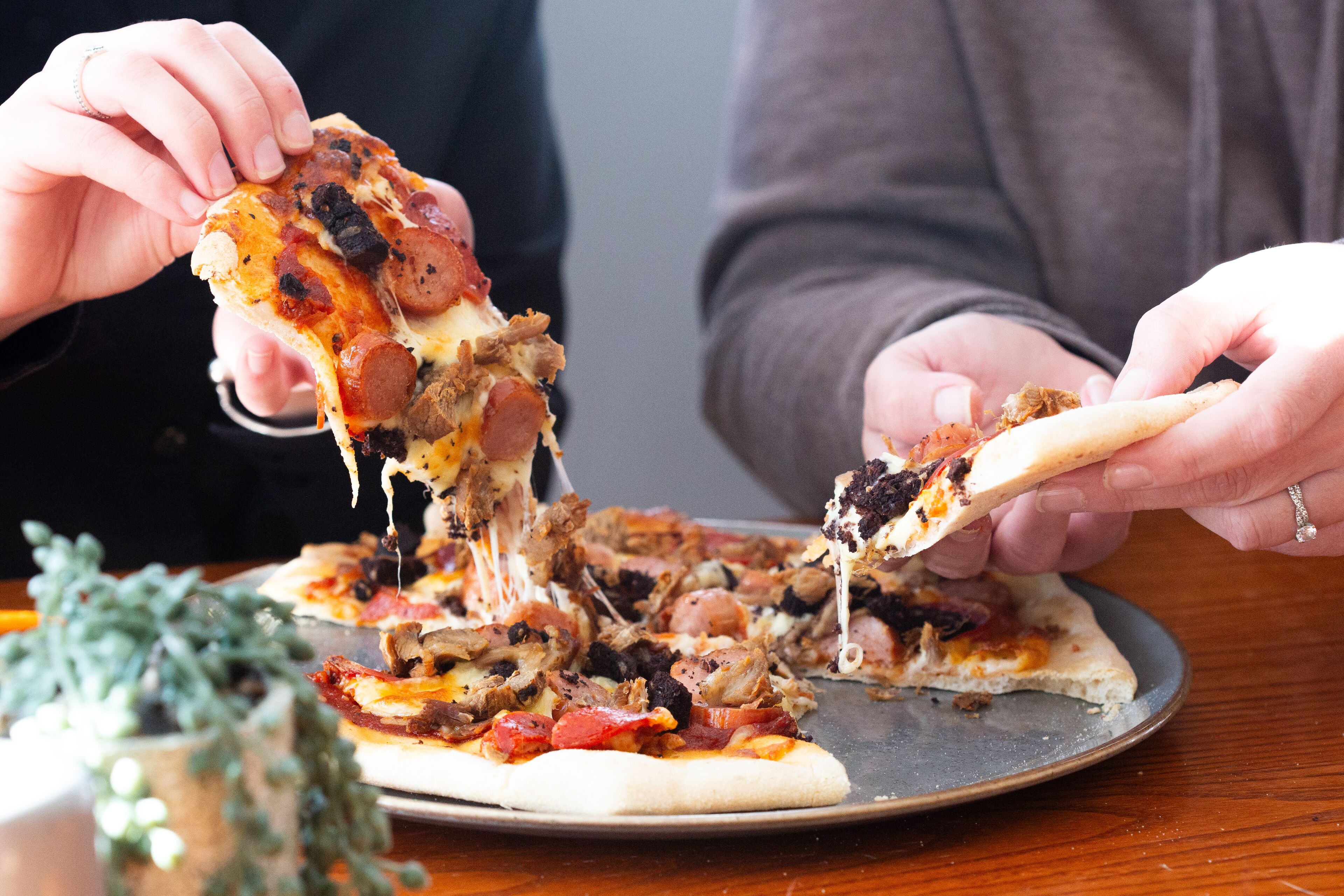 Une pizza garnie de divers ingrédients, servie sur un plateau en métal.