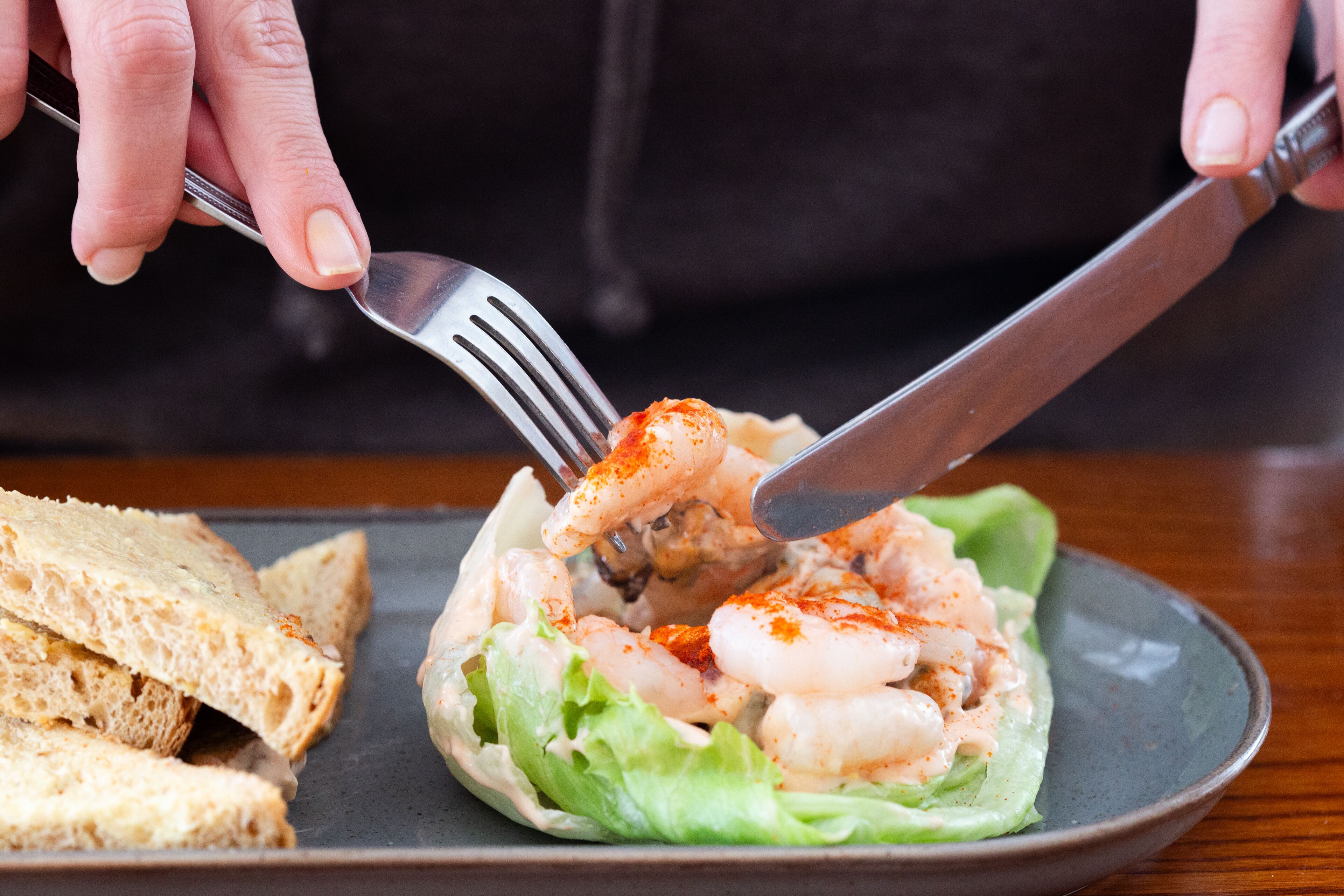 A plate with shrimp on lettuce, a fork, and a knife.