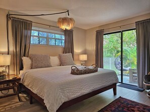 A spacious bedroom with a large bed, two bedside lamps, a hanging feathered light fixture, and a view of the outdoors through a sliding glass door. - 1 King, 2 Queen,1 twin, washer dryer, near parks &  FTL Marine center (Fort Lauderdale)