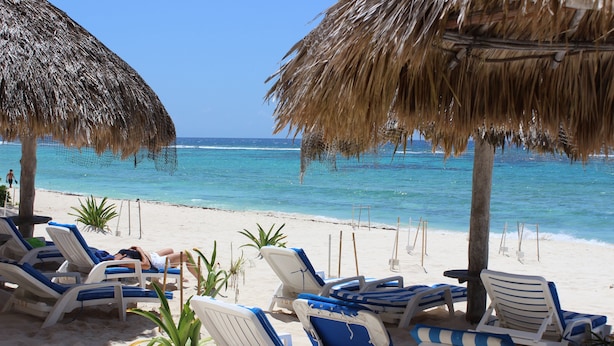Ein Strand mit Liegestühlen und Strohdächern.