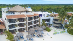 Ein Hotel mit mehreren Etagen, Strandlage und einem Poolbereich mit Sonnenschirmen.