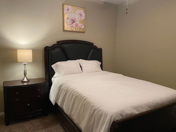 Una cama bien hecha con sábanas blancas en una habitación con paredes color beige.