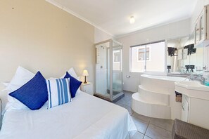 A hotel room with a bed, a bathroom with a bathtub, and a shower.