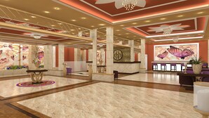 A spacious lobby with marble flooring, a reception desk, and a butterfly mural. - Europe Hotel & Casino (Sunny Beach)