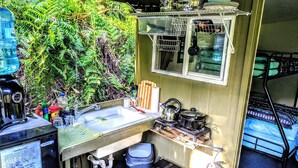 A compact kitchen with a sink, stove, and storage shelves.