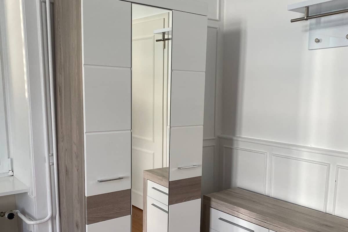 A room with a wardrobe, a mirror, and a countertop.