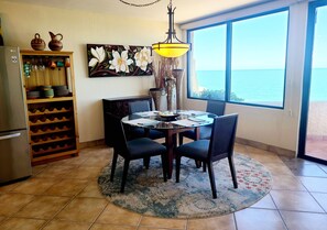 A dining area with a table, chairs, a rug, and a view of the ocean through a large window. - Beachfront Condo in a great location. (San Felipe)