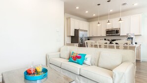 A modern kitchen with white cabinets, stainless steel appliances, and pendant lighting.