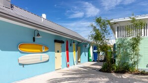 A pathway lined with surfboards on a building's exterior wall, leading to a door.