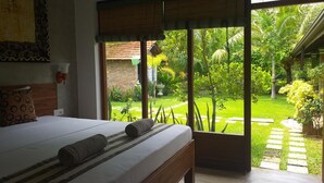 A bedroom with a large window, a bed, and a view of a garden. - Green wood villa (Negombo)