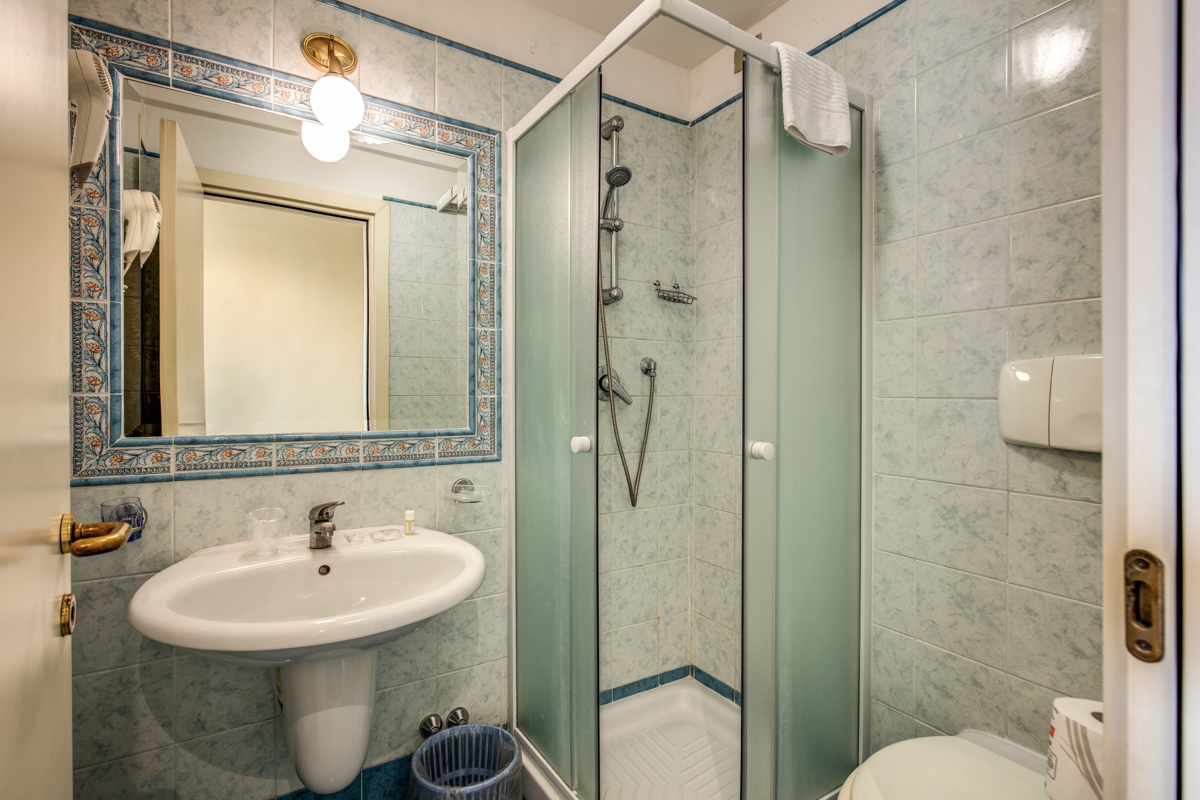 Et badeværelse med vask, spejl, bruser og toilet.