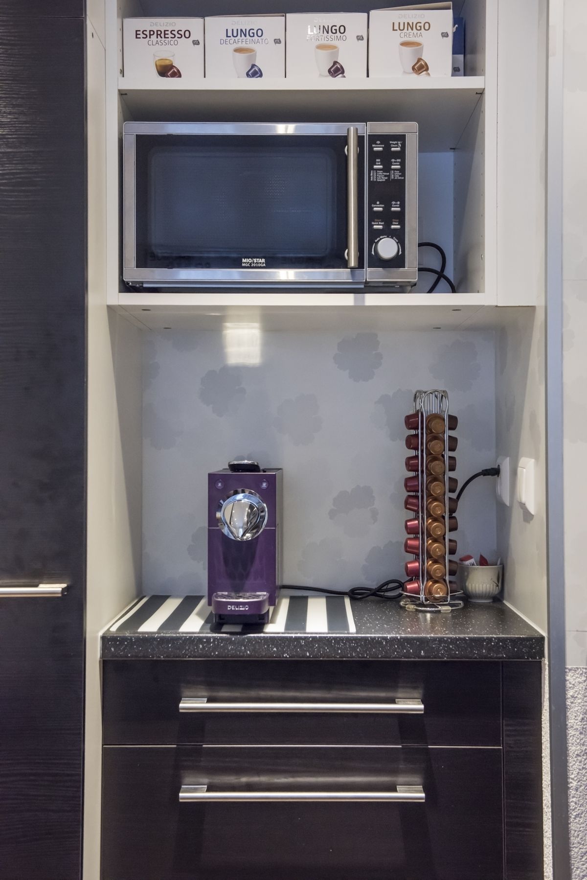 A compact kitchenette with a microwave, espresso machine, and a coffee bean dispenser.