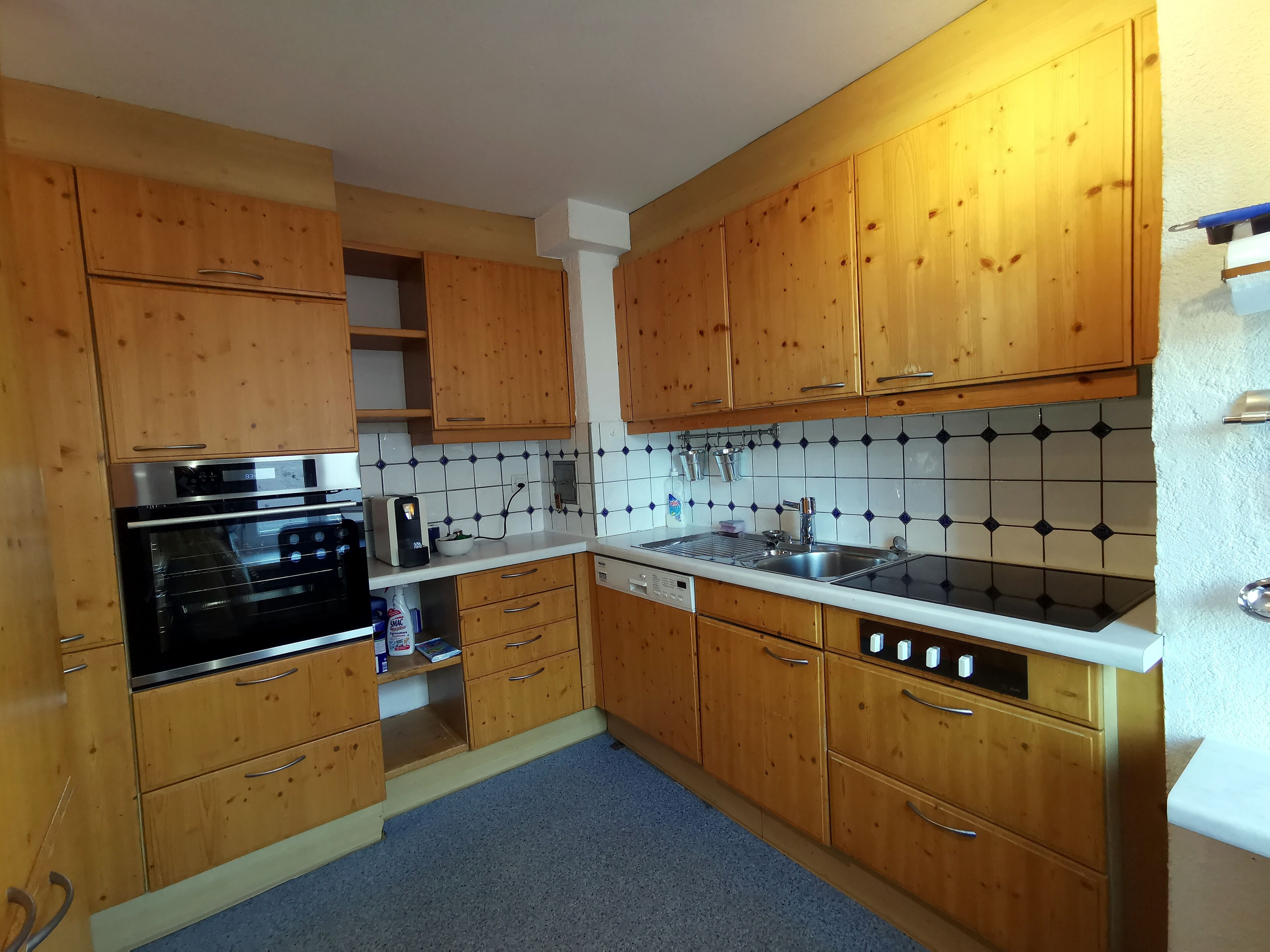 A kitchen with wooden cabinets, a built-in oven, a sink, and a tiled backsplash.