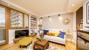 A modern living room with a sofa, coffee table, and ottoman, a television, and a decorative wall piece. - Golden Apartament by Your Freedom (Warsaw)