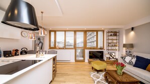 A modern kitchen with a large island, a dining area with a yellow chair, and a living room with a sofa and a coffee table. - Golden Apartament by Your Freedom (Warsaw)