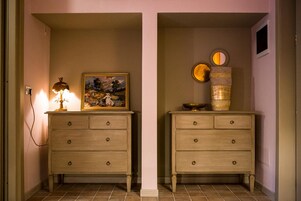 Dos cómodas de madera con cajones, una lámpara, un cuadro enmarco y un jarrón decorativo con un espejo.