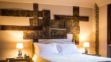 A hotel room with a bed, two bedside tables with lamps, a decorative wall piece, and a brick wall.