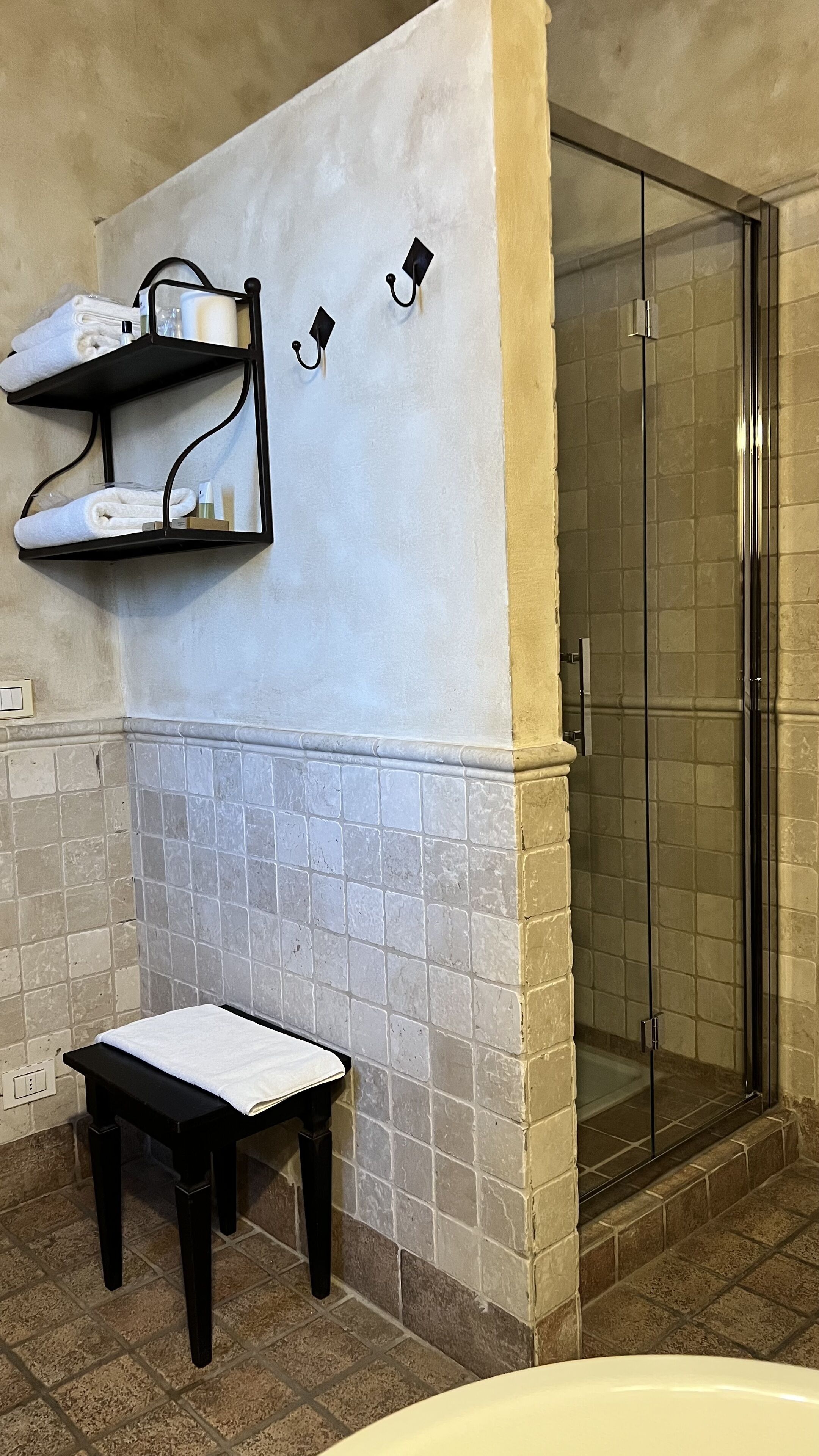 Une salle de bain avec une douche, un porte-serviettes et un petit banc.