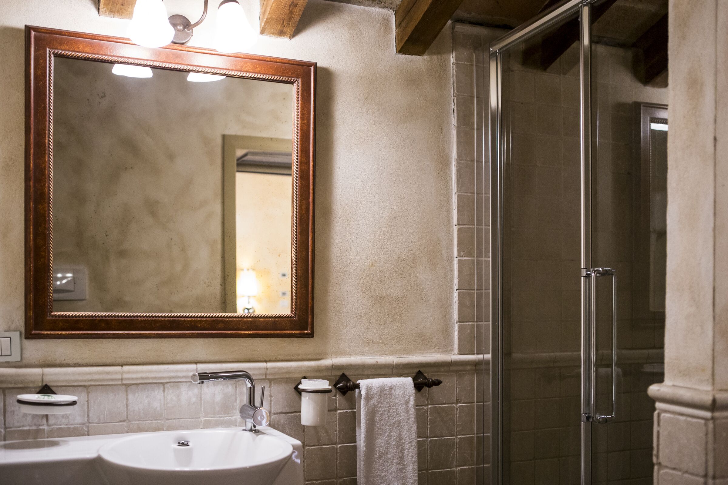 A bathroom with a large mirror, a sink, a towel rack, and a shower area.