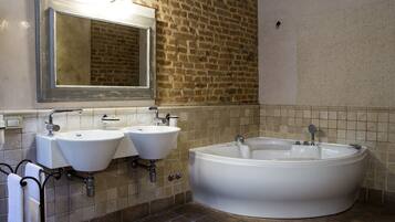Une salle de bain avec deux lavabos, une grande baignoire et un miroir au-dessus des lavabos.