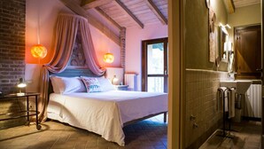 Une chambre à coucher avec un grand lit, une table de chevet, une lampe et une fenêtre avec des rideaux.