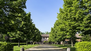 Une cour avec un chemin pavé, des bornes en pierre et, au fond, un bâtiment doté d’un toit en tuiles.