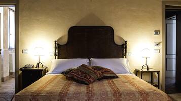 Un letto rifatto con cura, copriletto decorato e due cuscini ornamentali, affiancato da comodini con lampade.