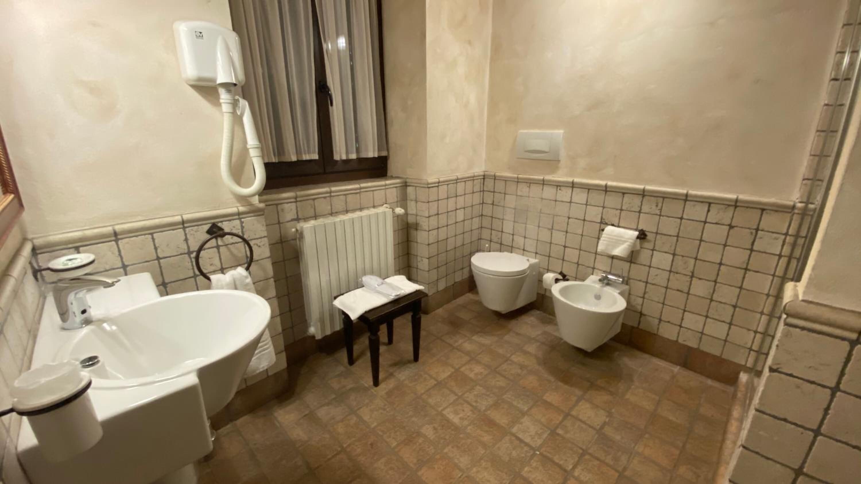 Un baño con lavabo, inodoro, bidé y radiador.
