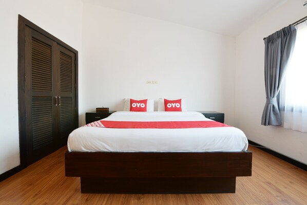 Une chambre à coucher avec un grand lit, deux tables de chevet, une armoire et une fenêtre avec des rideaux.