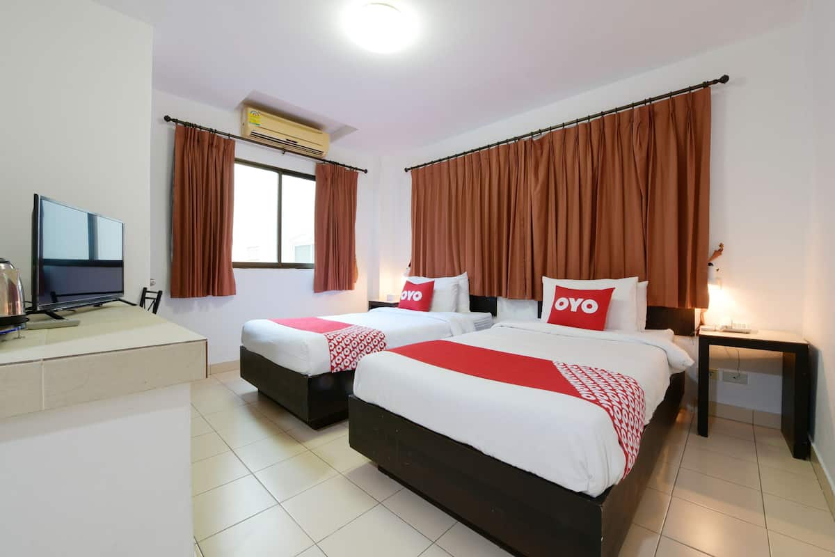 Een hotelkamer met twee bedden, een bureau, een televisie en een airconditioning.