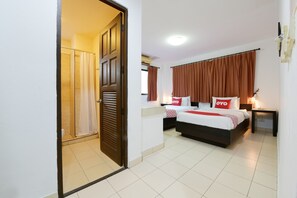 Une chambre d’hôtel comprenant un lit, une table de chevet, une commode, une fenêtre avec des rideaux, une porte et un espace douche.