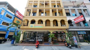 Un edificio de varios pisos con restaurante en la planta baja, balcones y letrero de casa de huéspedes.