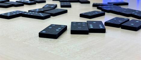 Dominoes scattered on a wooden surface with a sign reading "DOMINO" in the background.
