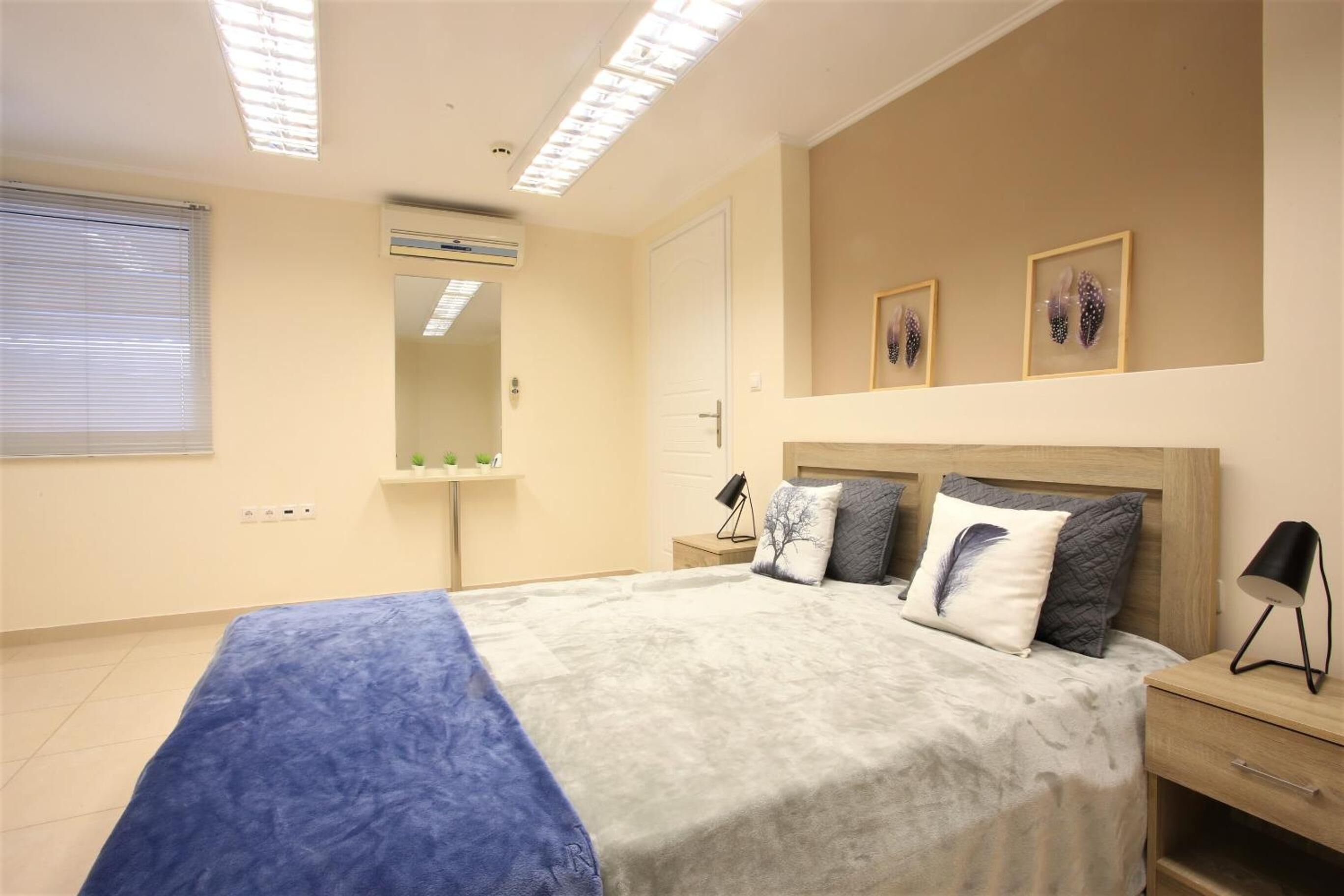 Un dormitorio con cama, mesita de noche, lámpara y una obra de arte colgada en la pared.