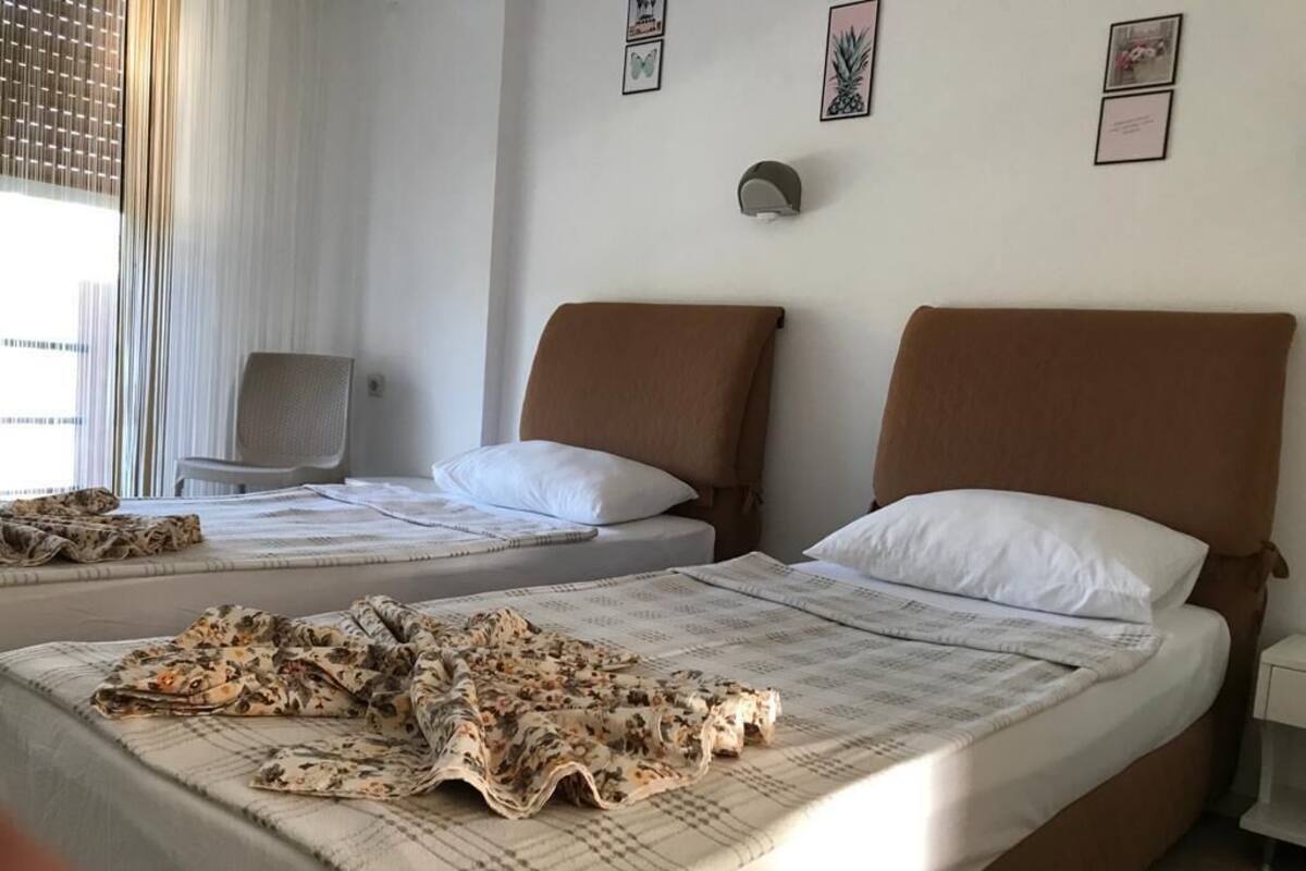 A hotel room with two beds, a chair, and a window with blinds.