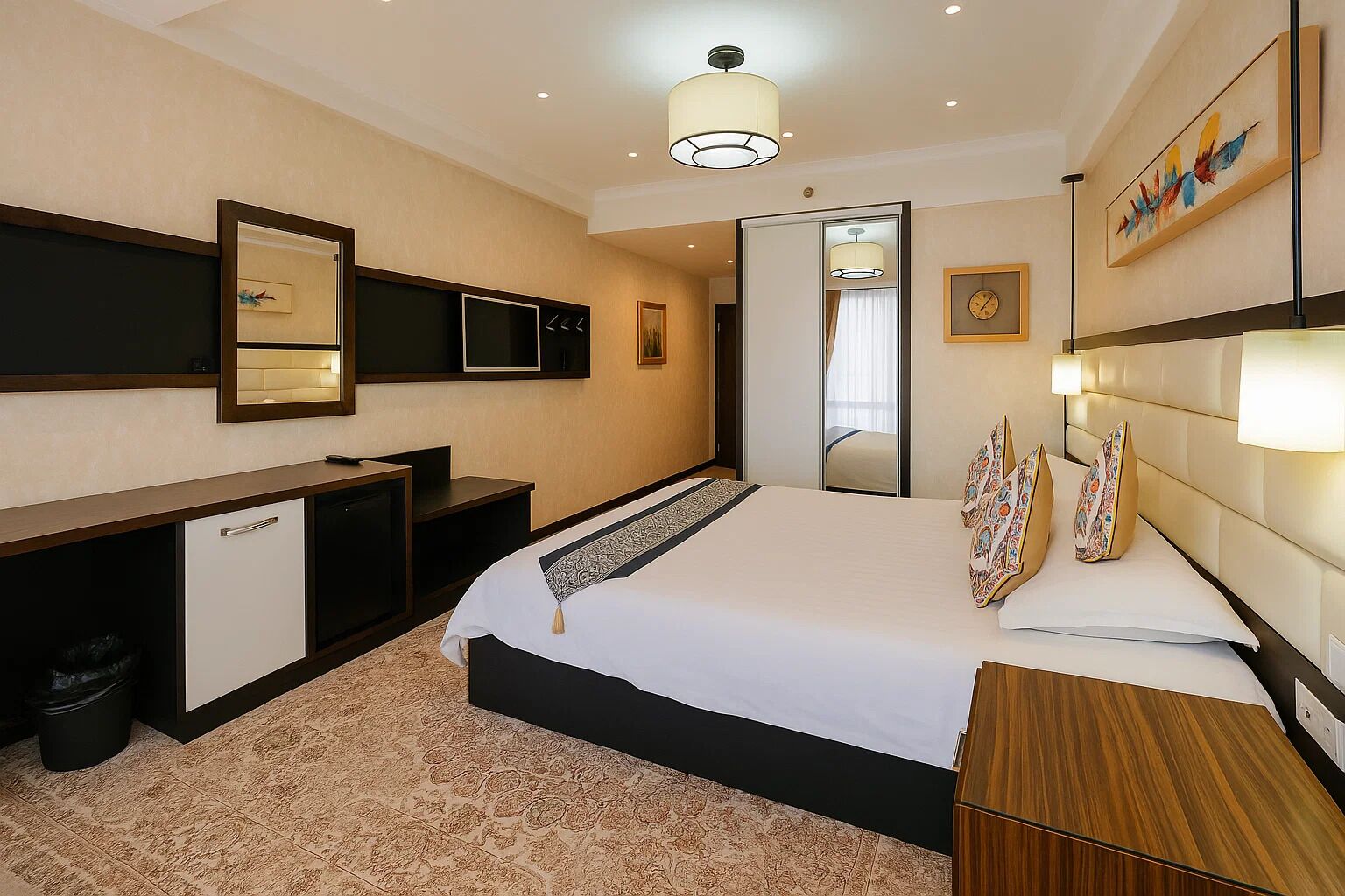 A hotel room with a bed, bedside tables, a desk, a mirror, and a wardrobe.