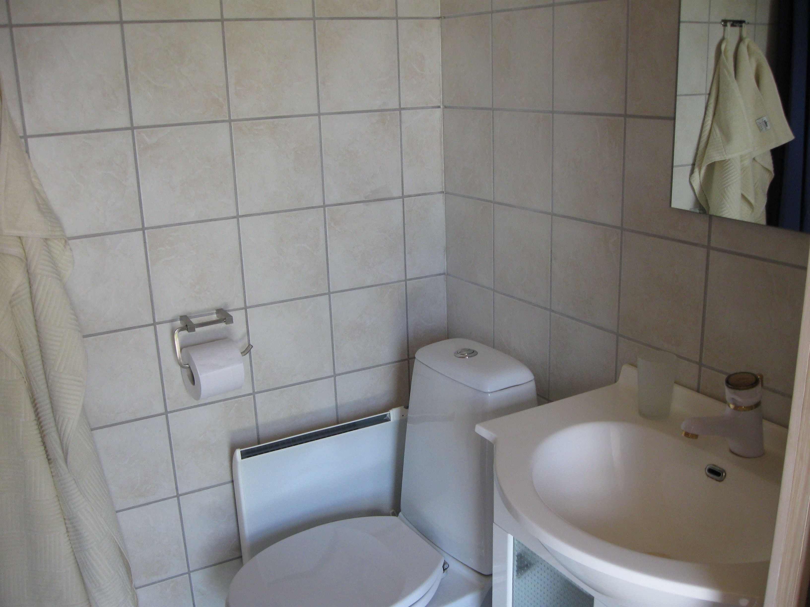 A small bathroom with a toilet, sink, and towel hanging on the wall.