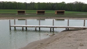 A wooden dock extending into a calm body of water with a sandy shore. - Koebenhovedskov Bed & Breakfast (Rodding)