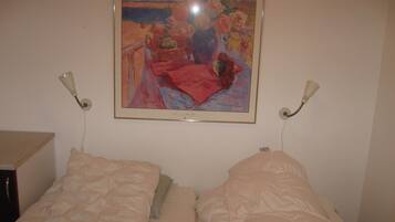 A bedroom with two beds, a painting on the wall, and bedside lamps.
