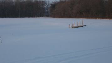 A snowy landscape with a wooden dock extending into a frozen body of water.