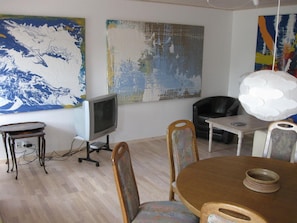 Relax in a stylish living room with a large abstract painting, flat-screen TV, and comfortable dining area.