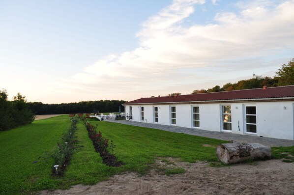 A white building with a red roof, a paved pathway, and a well-maintained lawn.